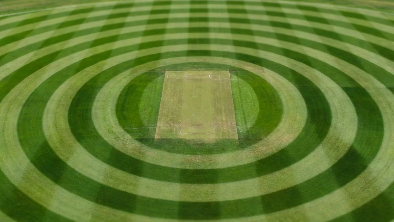 Aerial view of a cricket field with mowing rings around the central square